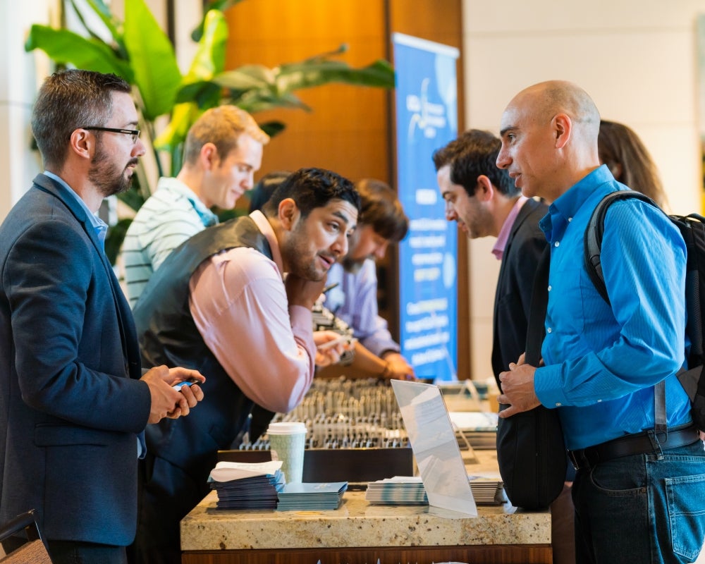 Attendees standing around the registration table with participant badges and brochures