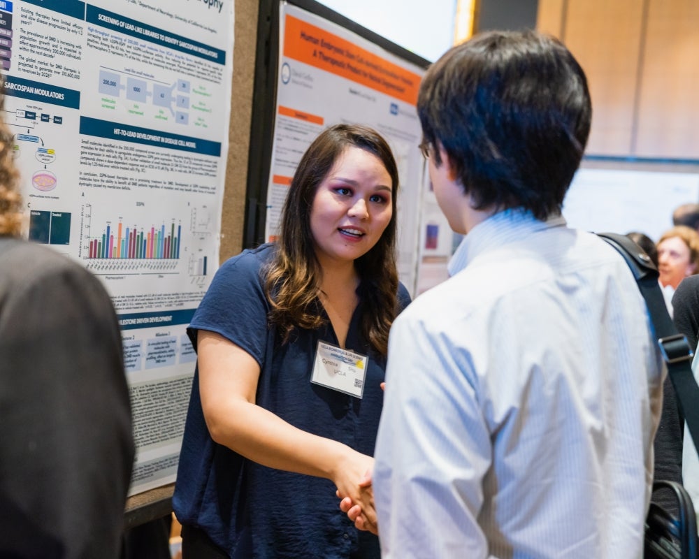 A young female attendee shakes the hand of a male attendee