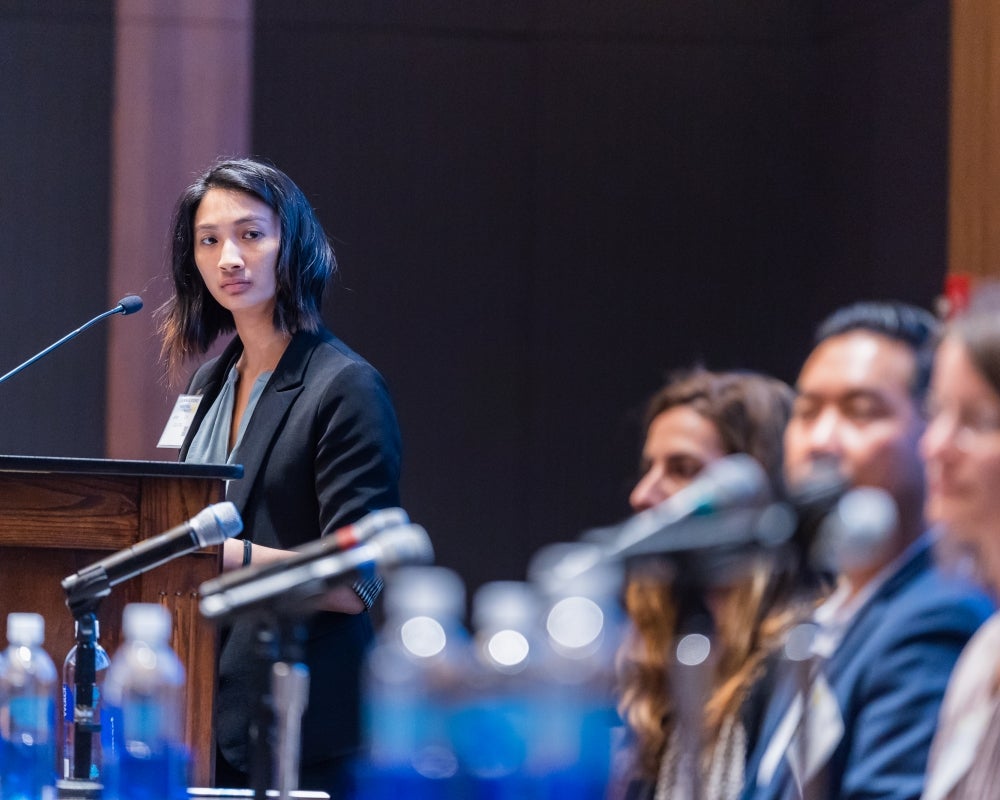 Moderator listens from the podium as a panel member speaks