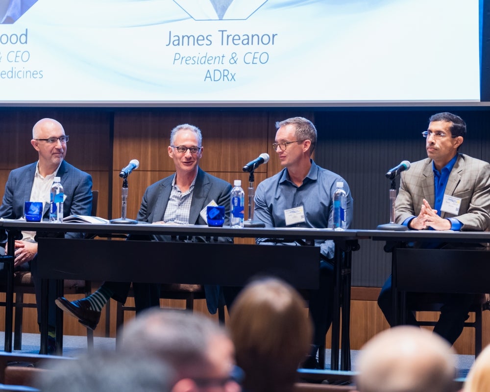 Four panel members seated at a table on the stage