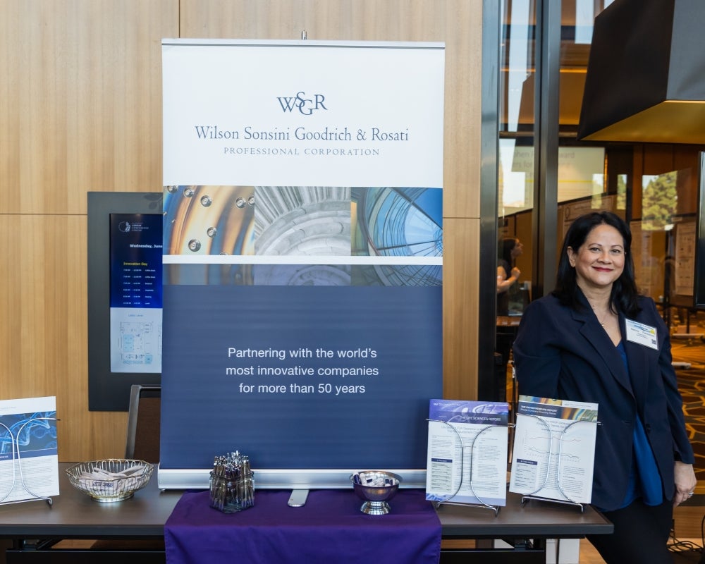 Woman smiling as she works at the Wilson Sonsini Goodrich & Rosati exhibitor table